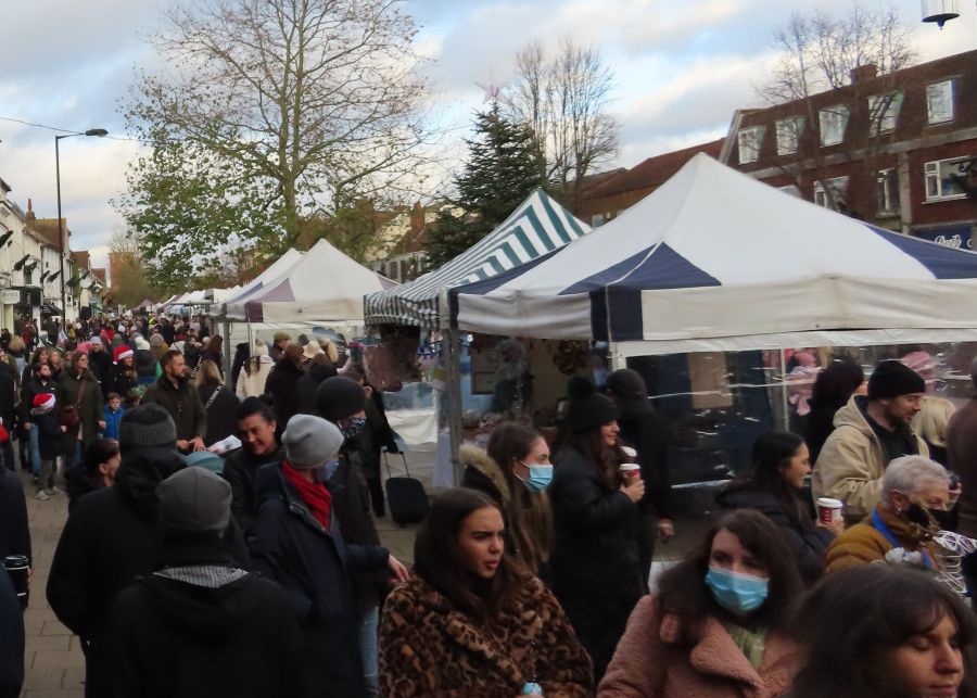 A row of canvas pagodas over market stalls with crowds of people
