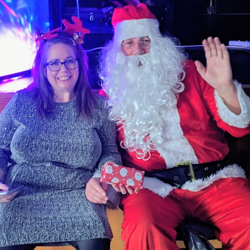 A smiling young lady with a waving Santa Claus